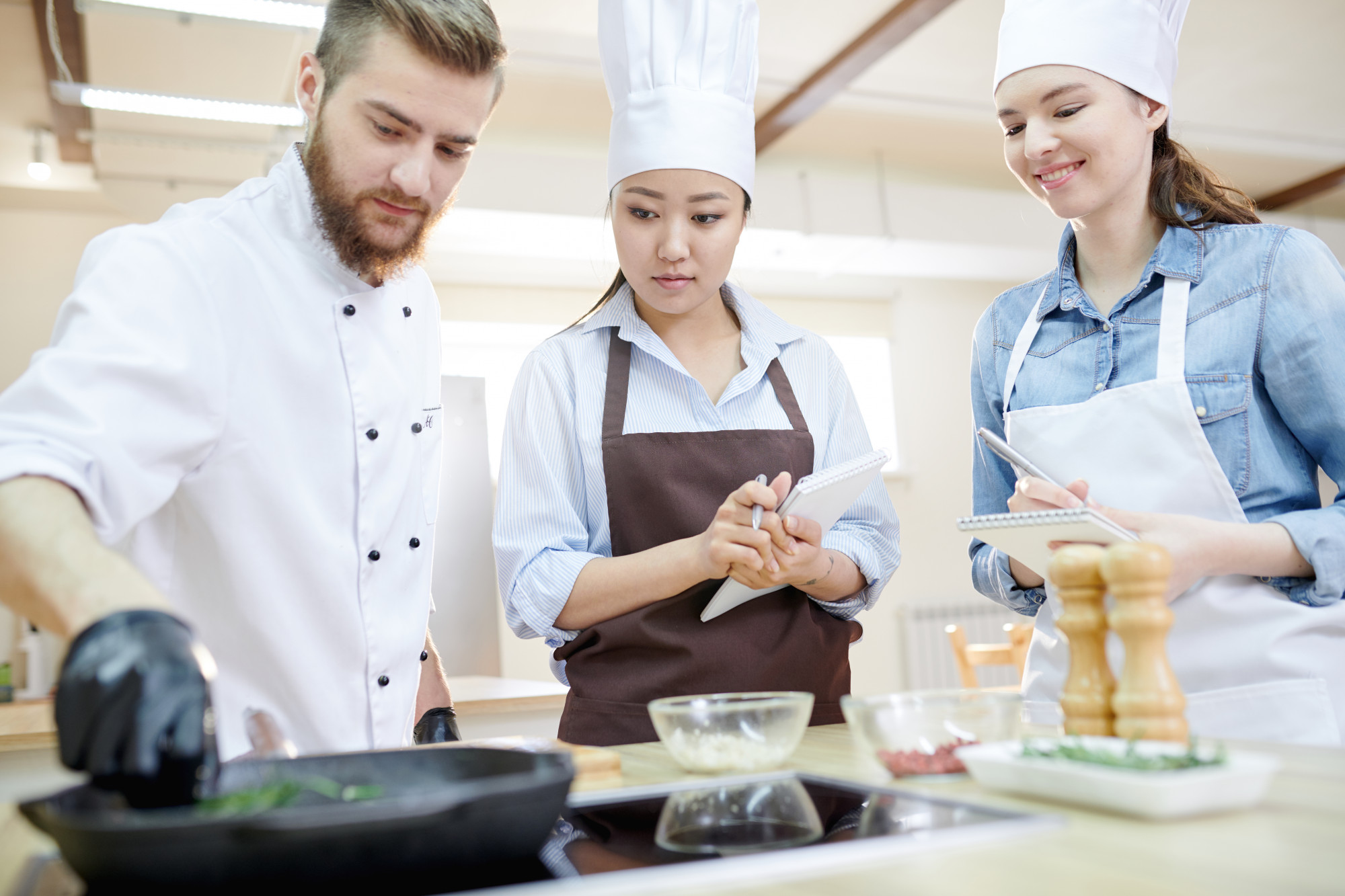 Chef demonstrating a technique to students in a modern kitchen